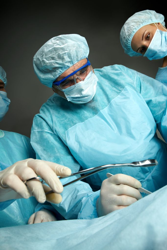side view of three surgeons operating