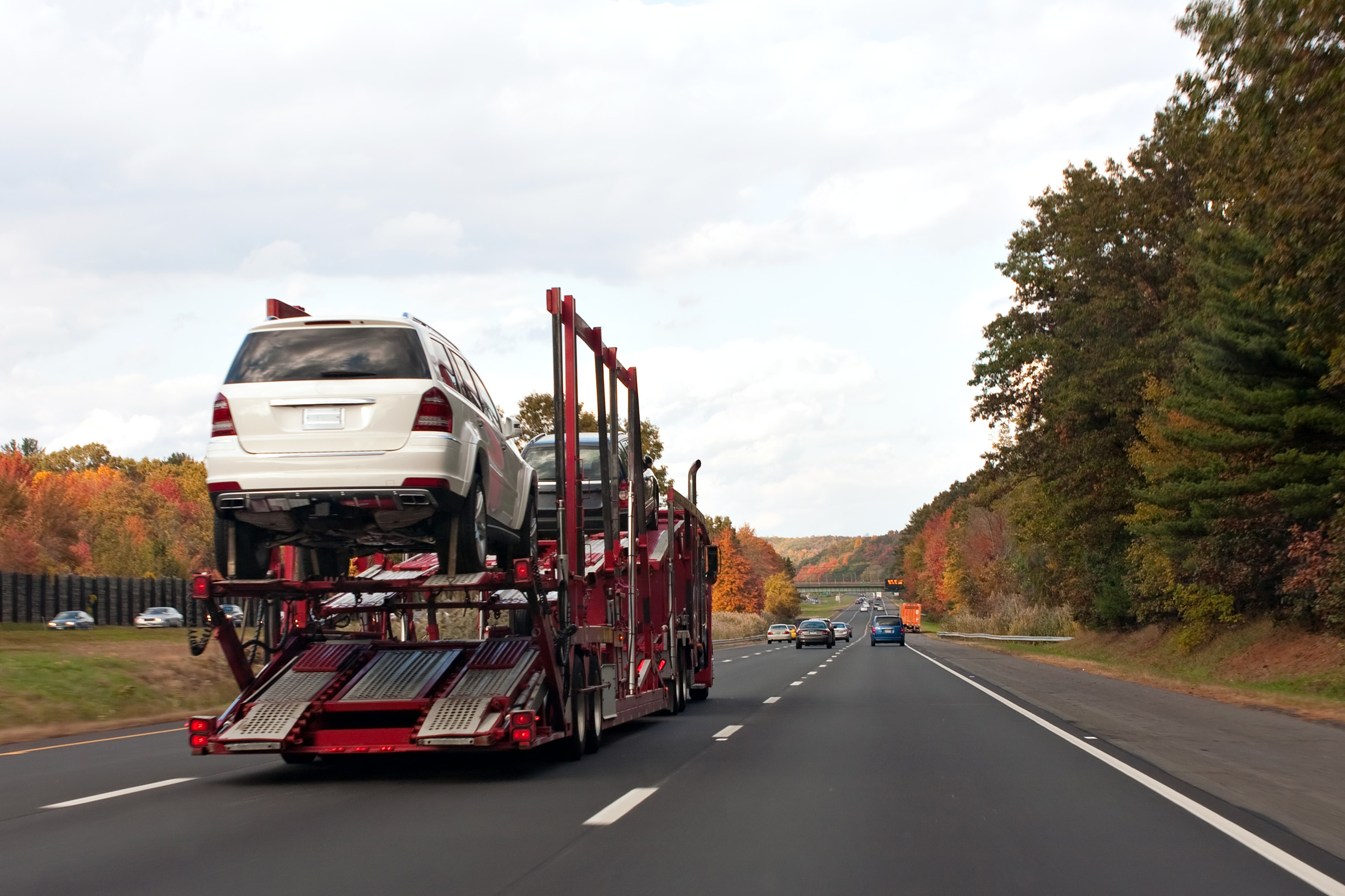 an automotive car carrier truck driving down the highway with a full load of new vehicles SYRbHsv0So