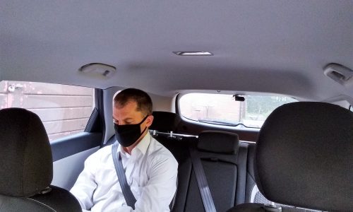 Man in back of taxi wearing a mask